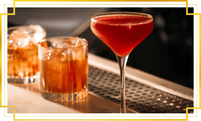 Three red cocktails on a bar