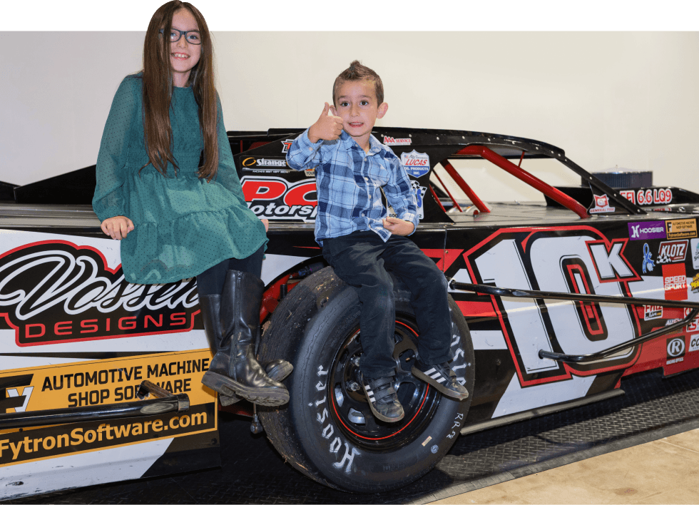 Two kids sitting on a car at the San Diego Automotive Museum