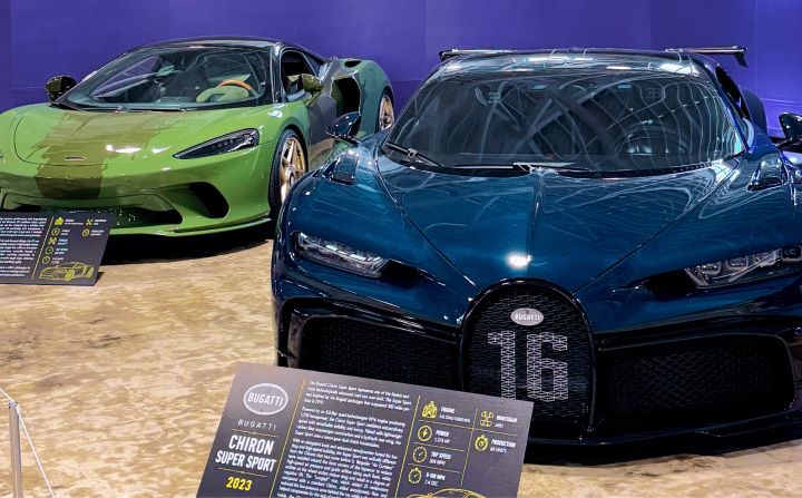 A green 2022 McLaren GT and a blue 2018 Bugatti Chiron on display at the San Diego Automotive Museum in the Numinous Hypercars Titans of Speed exhibit.