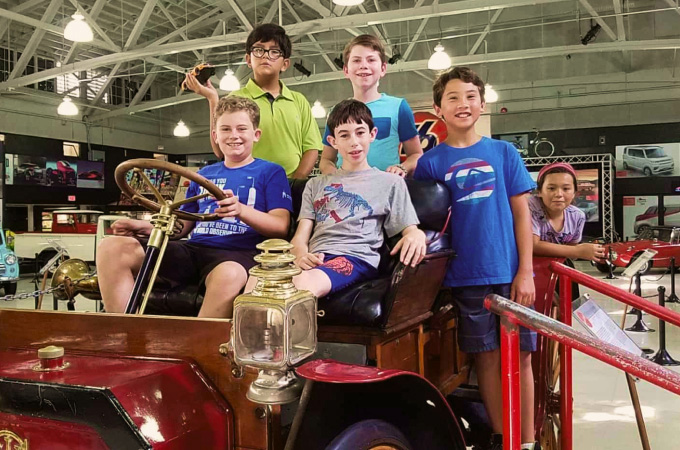 Students sitting in a car at the San Diego Automotive Museum enjoying a school program