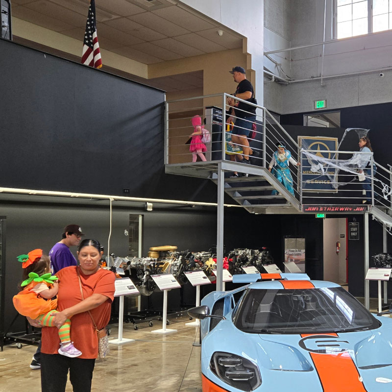 A mom and her kid walking around the cars dressed as pumpkins for Halloween